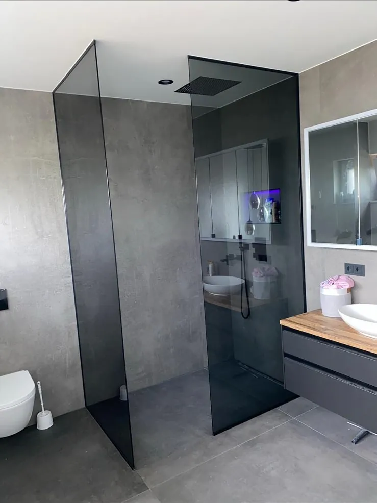 Walk-in-Dusche aus getöntem Grauglas in einem Bad in Betonoptik