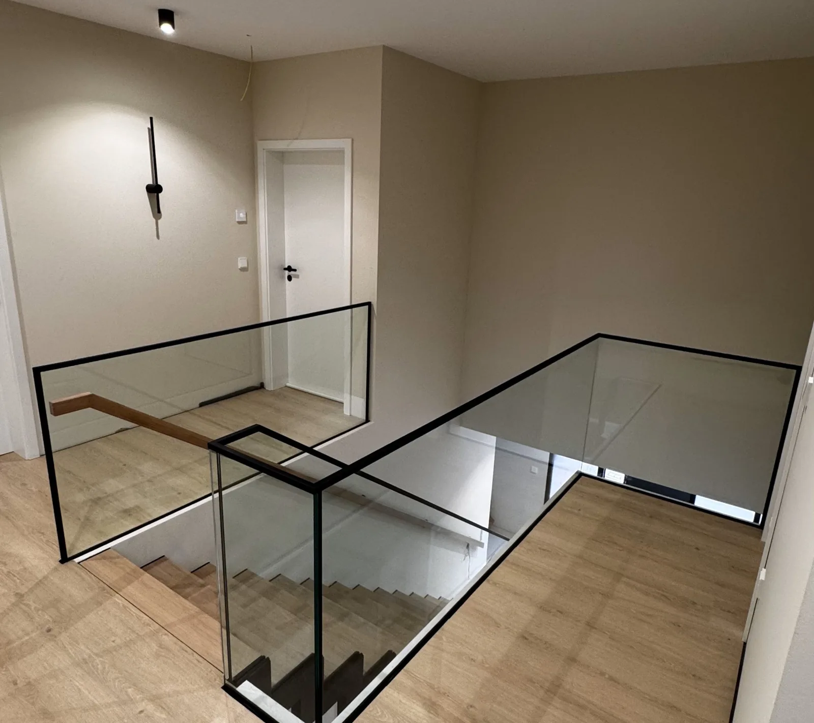 Ganzglasgeländer mit schwarzem Handlauf an einer Galerie mit Holzboden, Merzig